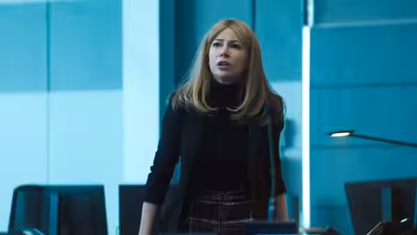 Anne Weying (Michelle Williams) stands in a blue-lit laboratory