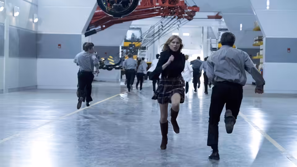 Anne Weying (Michelle Williams) runs through a laboratory as people flee behind her
