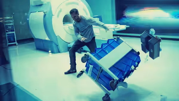 Eddie Brock (Tom Hardy) stumbles beside a toppled medical cart in a laboratory