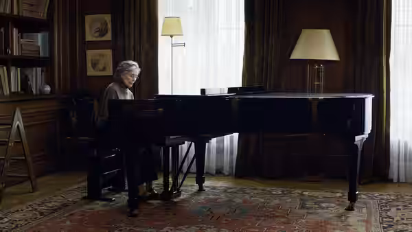 Anne (Emmanuelle Riva) playing the grand piano in a curtained living room