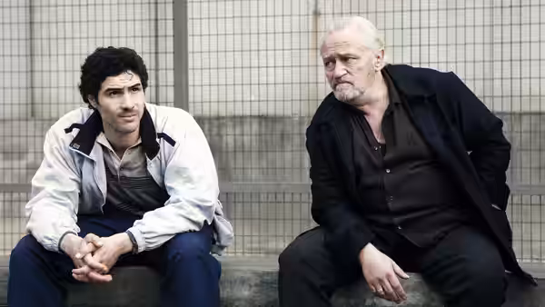 Malik (Tahar Rahim) and César (Niels Arestrup) sitting together on a bench