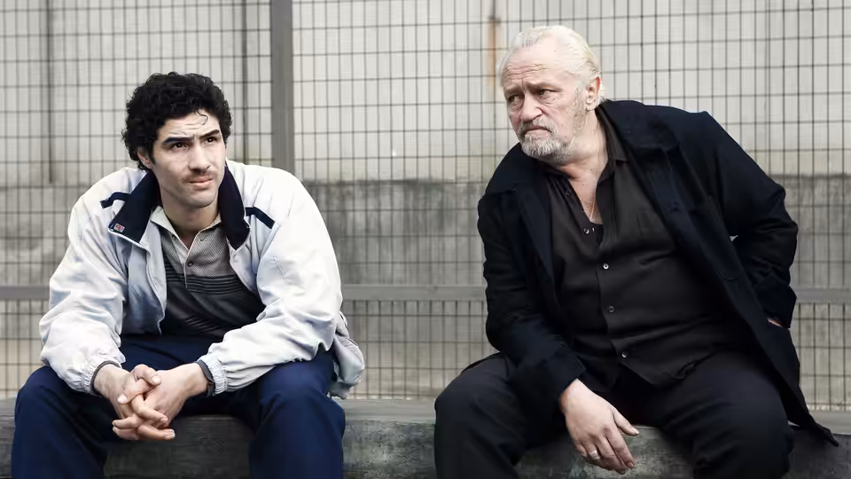 Malik (Tahar Rahim) and César (Niels Arestrup) sitting together on a bench