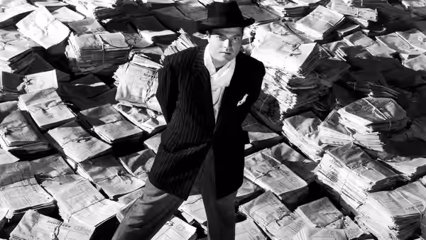 Charles Foster Kane (Orson Welles) standing on stacks of newspapers