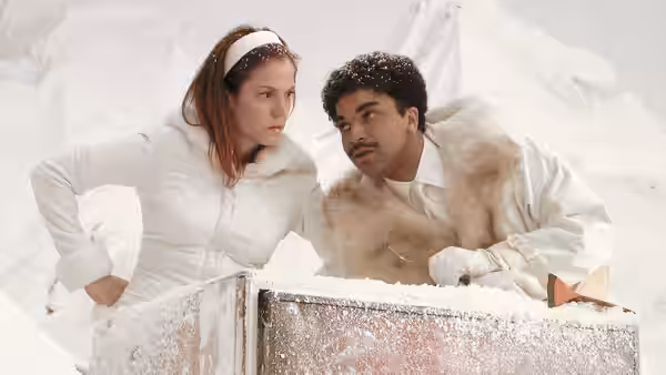 a woman and man in white winter coats stand in snow
