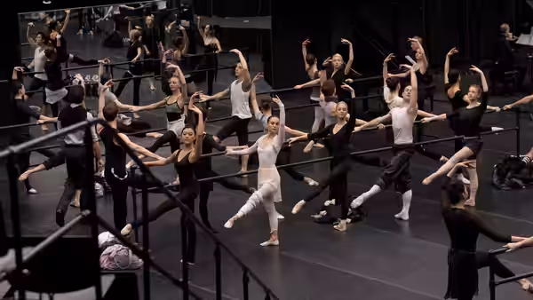 Ballet dancers practicing at the barre in a mirrored studio