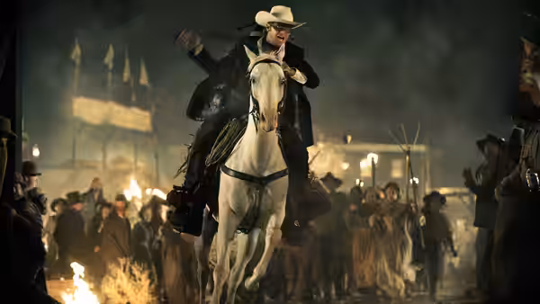 The Lone Ranger (Armie Hammer) riding a white horse through a burning crowd