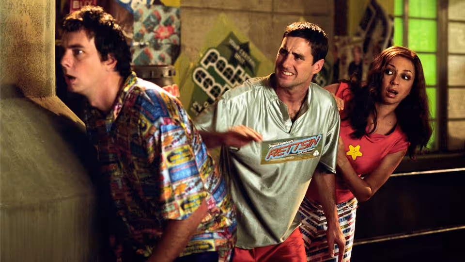 Joe Bauers (Luke Wilson), Frito (Dax Shepard) and Rita (Maya Rudolph) looking alarmed while peeking around a corner