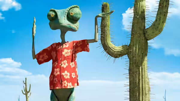 Green chameleon waving one hand beside tall cactus under blue sky