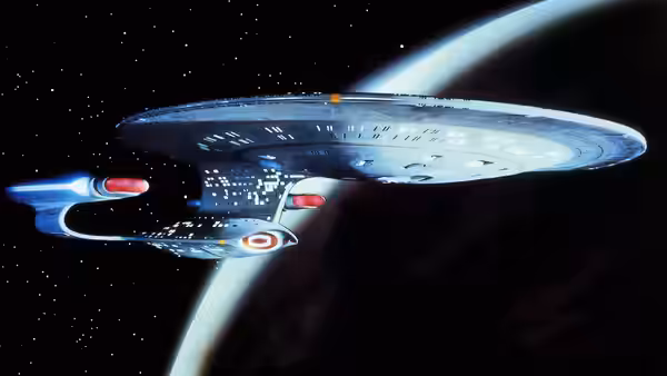 USS Enterprise-D flying past a planet with rings in space