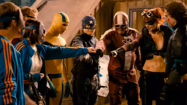 Masked vigilantes in colorful costumes gathered around a table