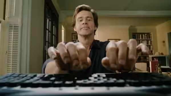Bruce Nolan (Jim Carrey) typing energetically at a keyboard while smiling