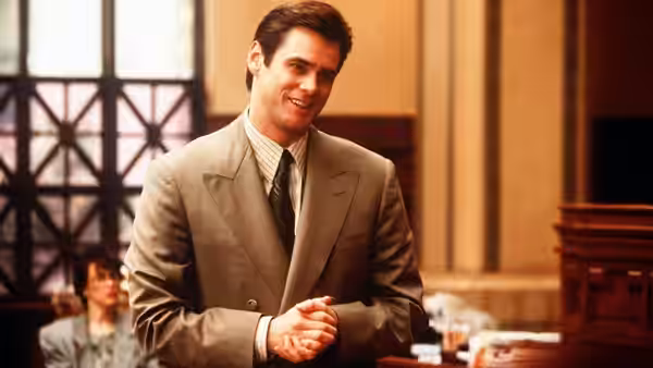 Fletcher Reede (Jim Carrey) smiling with hands clasped in courtroom