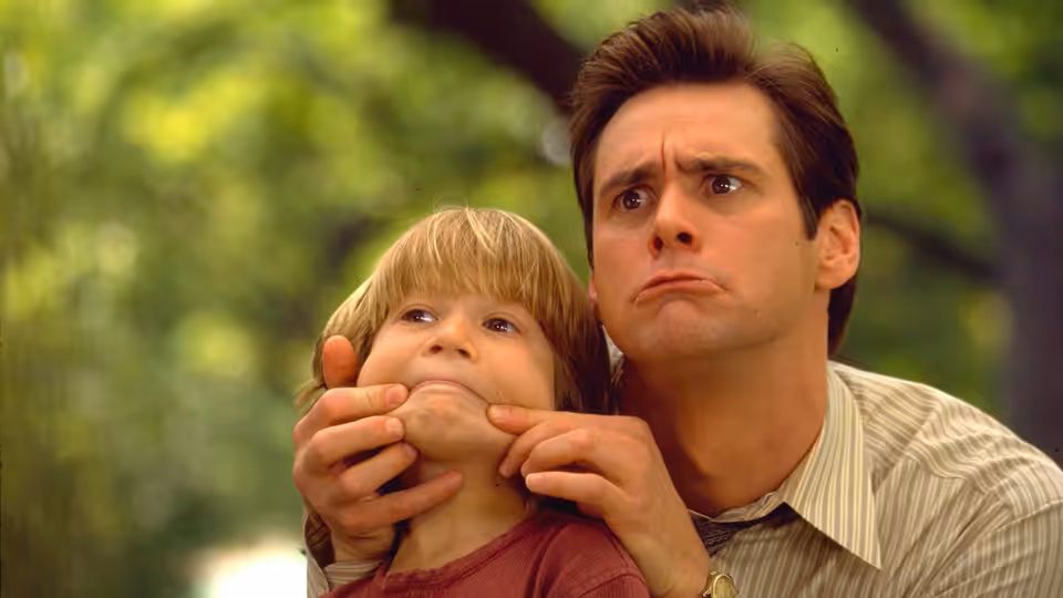 Fletcher Reede (Jim Carrey) holding a boy's chin outdoors