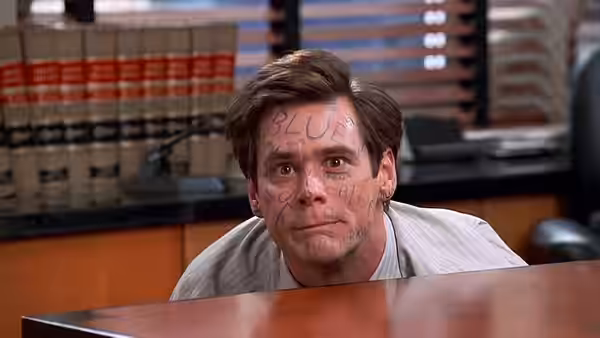 Fletcher Reede (Jim Carrey) with words written on his face at desk