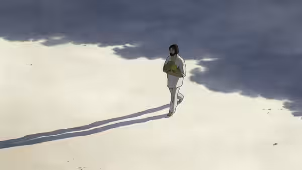 A man in white clothing walks across pale ground carrying a bundle