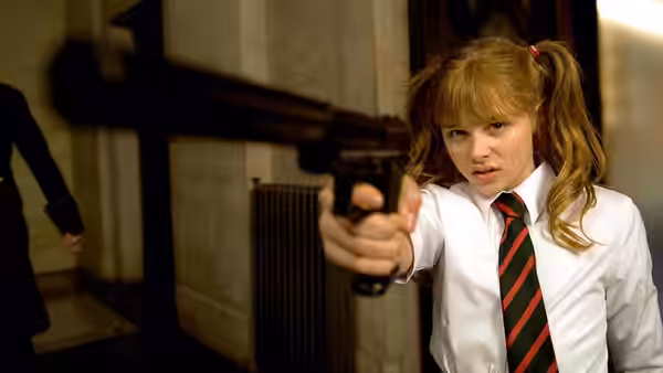 Hit Girl (Chloë Grace Moretz) aiming a pistol in school uniform