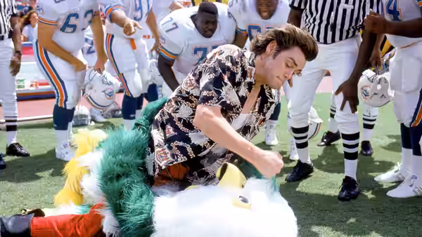 Ace Ventura (Jim Carrey) grapples with a mascot on a football field
