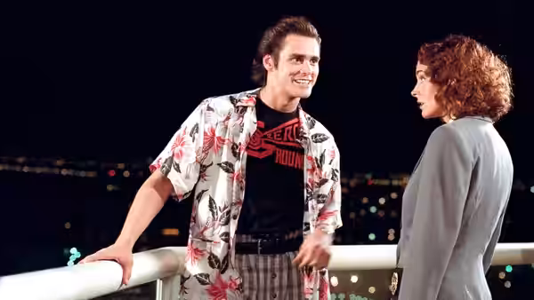 Ace Ventura (Jim Carrey) smiles at Einhorn (Sean Young) on a night balcony