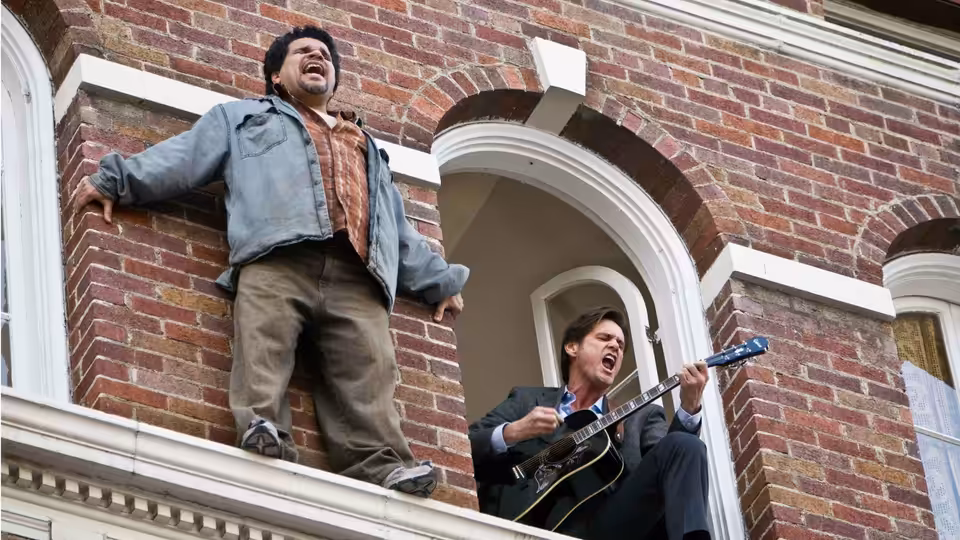 Two men sing from the ledge outside a brick building