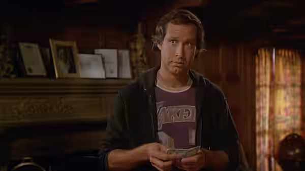 Fletch holds folded cash in a wood-paneled room
