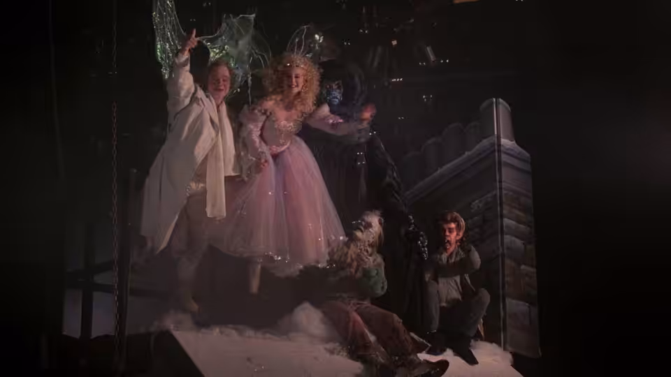 The Ghost of Christmas Present and a woman in a pink dress tower over a man in snow
