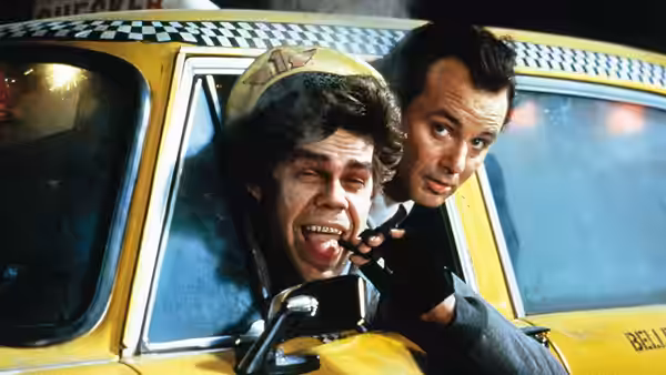 Francis Cross (Bill Murray) leans from a yellow taxi beside a grimacing passenger