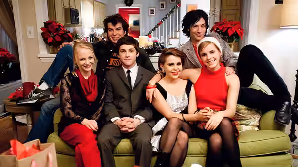 a group of friends pose together on a green couch in a living room