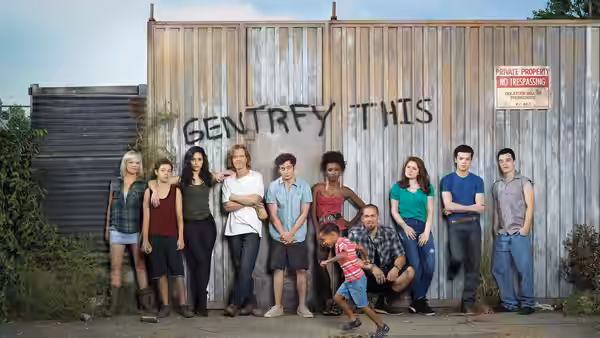 Group of young adults and children posing against a graffiti-covered fence