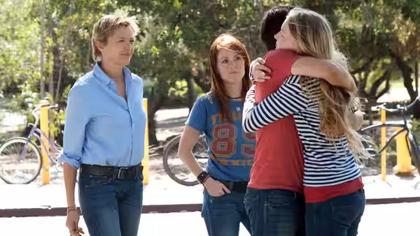 Nic (Annette Bening) stands beside Jules (Julianne Moore) hugging their daughter outdoors
