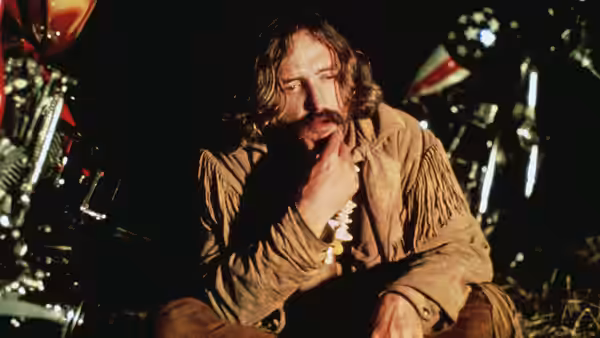 Wyatt (Peter Fonda) sits in a fringed jacket, resting his chin on his hand