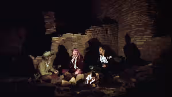 Three people sit together in a dim brick room