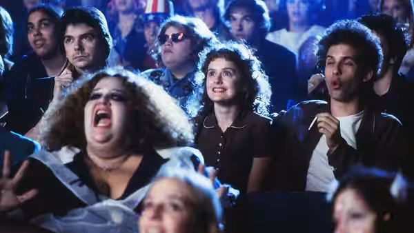 Students cheer and sing along together in a crowded auditorium