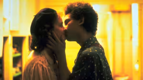 A young couple kiss in a warmly lit room