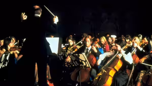 An orchestra performs as its conductor leads from the podium
