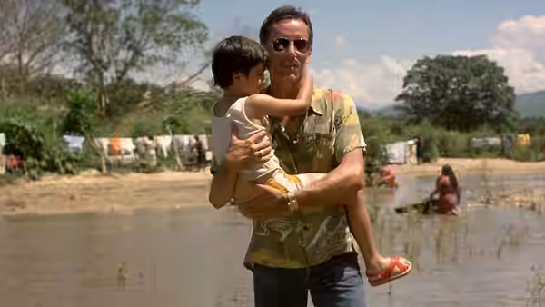 Richard Boyle (James Woods) carries a child through a flooded village