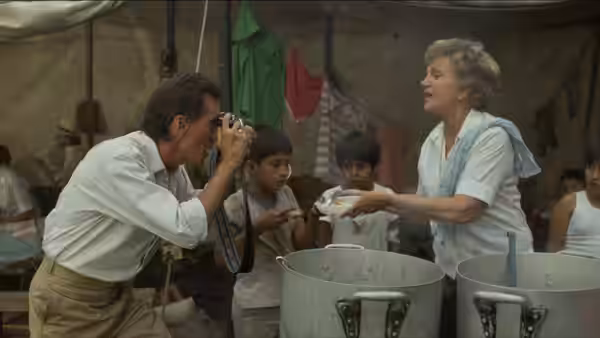 Richard Boyle (James Woods) photographs a woman serving food to children in a camp