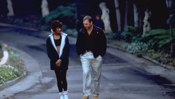 Rachel Marron (Whitney Houston) walks beside Frank Farmer (Kevin Costner) along a driveway