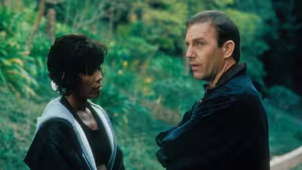 Rachel Marron (Whitney Houston) speaks with Frank Farmer (Kevin Costner) outdoors among trees