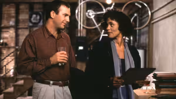 Frank Farmer (Kevin Costner) talks with Rachel Marron (Whitney Houston) in a room with recording equipment