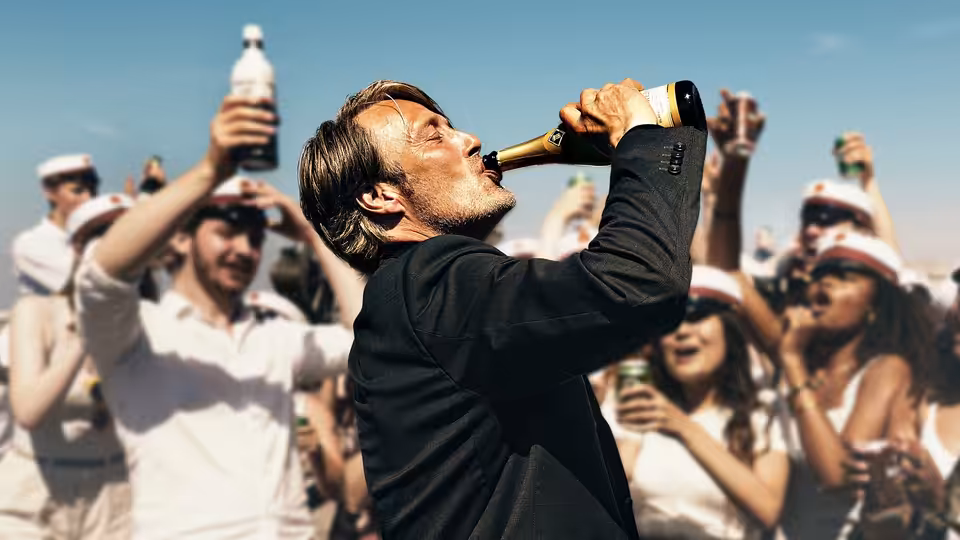 Martin (Mads Mikkelsen) drinks from a bottle as students celebrate around him