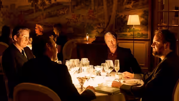 Martin, Tommy, Nikolaj, and Peter share dinner around a candlelit restaurant table