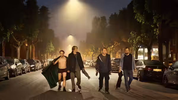 Martin, Tommy, Nikolaj, and Peter walk down a city street at night