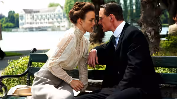 Sabina Spielrein (Keira Knightley) and Carl Jung (Michael Fassbender) sit close on a bench