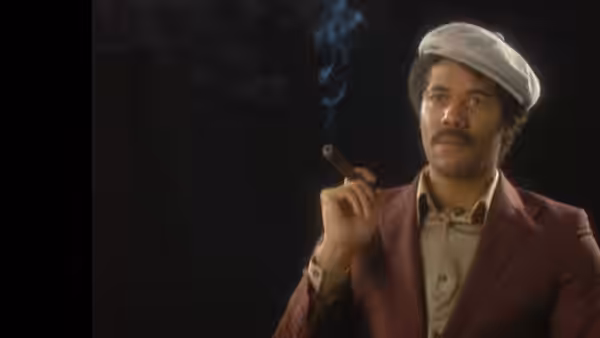 Garth Marenghi (Matthew Holness) holding a lit cigar to his mouth
