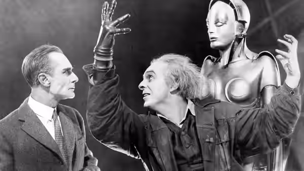 Rotwang gesturing beside the Machine Man as Fredersen watches