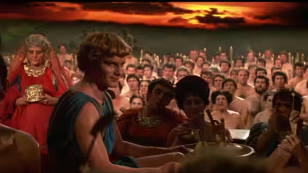 Encolpio (Martin Potter) sits at a banquet before a crowd of diners