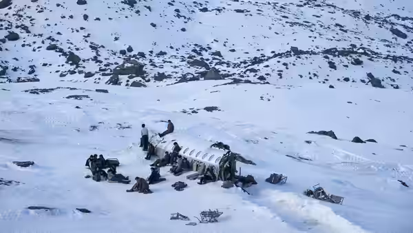 Survivors gather around a plane wreck scattered across a snowy mountainside
