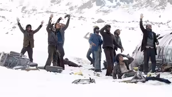 Survivors raise their arms beside the wreckage in a snowy mountain basin