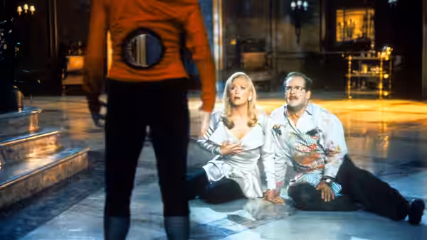 Lisle von Rhuman (Isabella Rossellini) faces Madeline Ashton and Ernest Menville seated on the floor