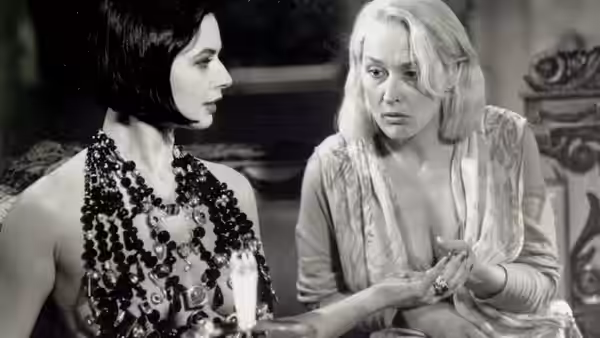 Lisle von Rhuman (Isabella Rossellini) studies Helen Sharp's hands as Helen looks alarmed
